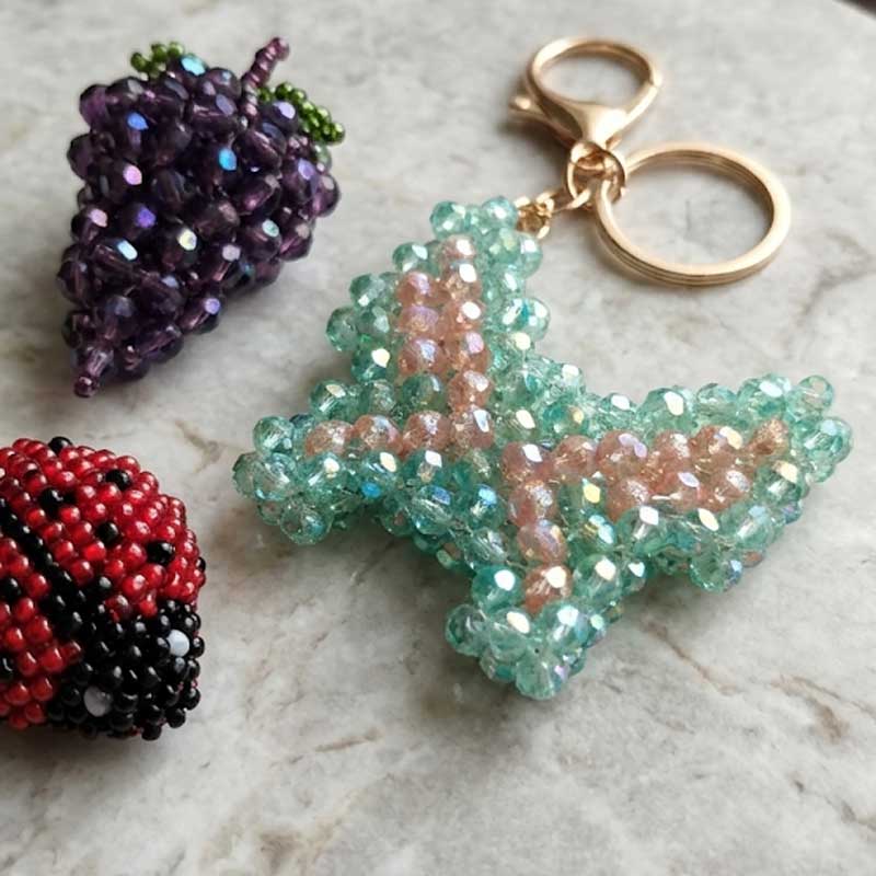 Porte-clés DORÉA Crystal Butterfly Mint Blush fait main en perles acryliques effet cristal vert menthe et rose poudré avec mousqueton doré en acier inoxydable.